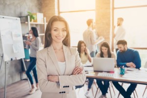 One for all and all for one. Success concept. Cheerful young lady is with partners in modern light office, smiling, standing in formal wear